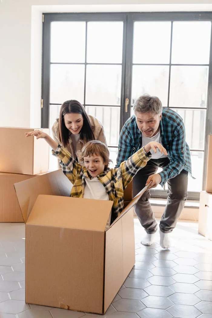 our-journey-01 Happy family playing with boxes while moving into a new home, full of joy and excitement.